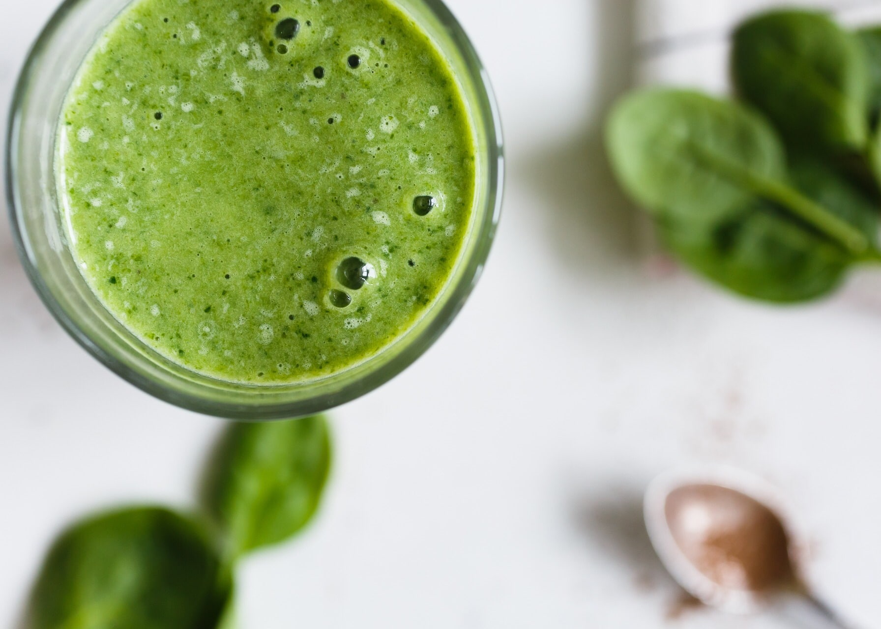 Green smoothie with brass spoon